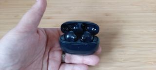 A pair of black Tranya Nova earbuds sitting on a wooden desk