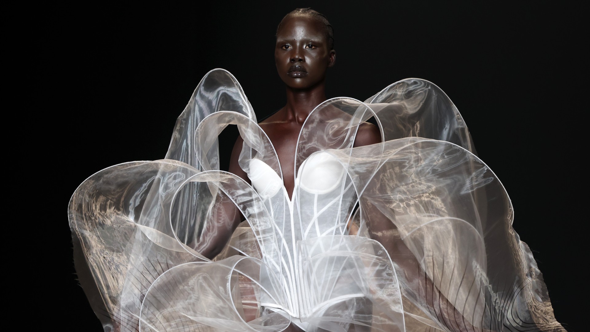 A runway model wearing a white sculptural gown