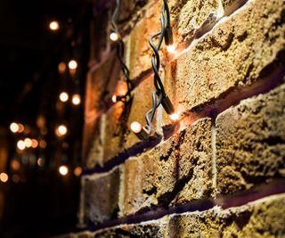 A close up of Christmas lights on a brick wall