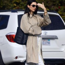 Kendall Jenner wearing a long silk scarf around her waist with a trench coat, white jeans, and ballet flats.