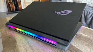 Asus ROG Strix Scar 18 gaming laptop with lid half closed on a wooden table