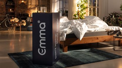 best bed in a box mattress: Emma mattress bed in a box packaged up and displayed next to a bed