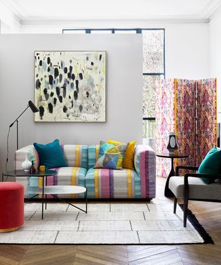 A colorful living room with patterned sofa and abstract modern art.