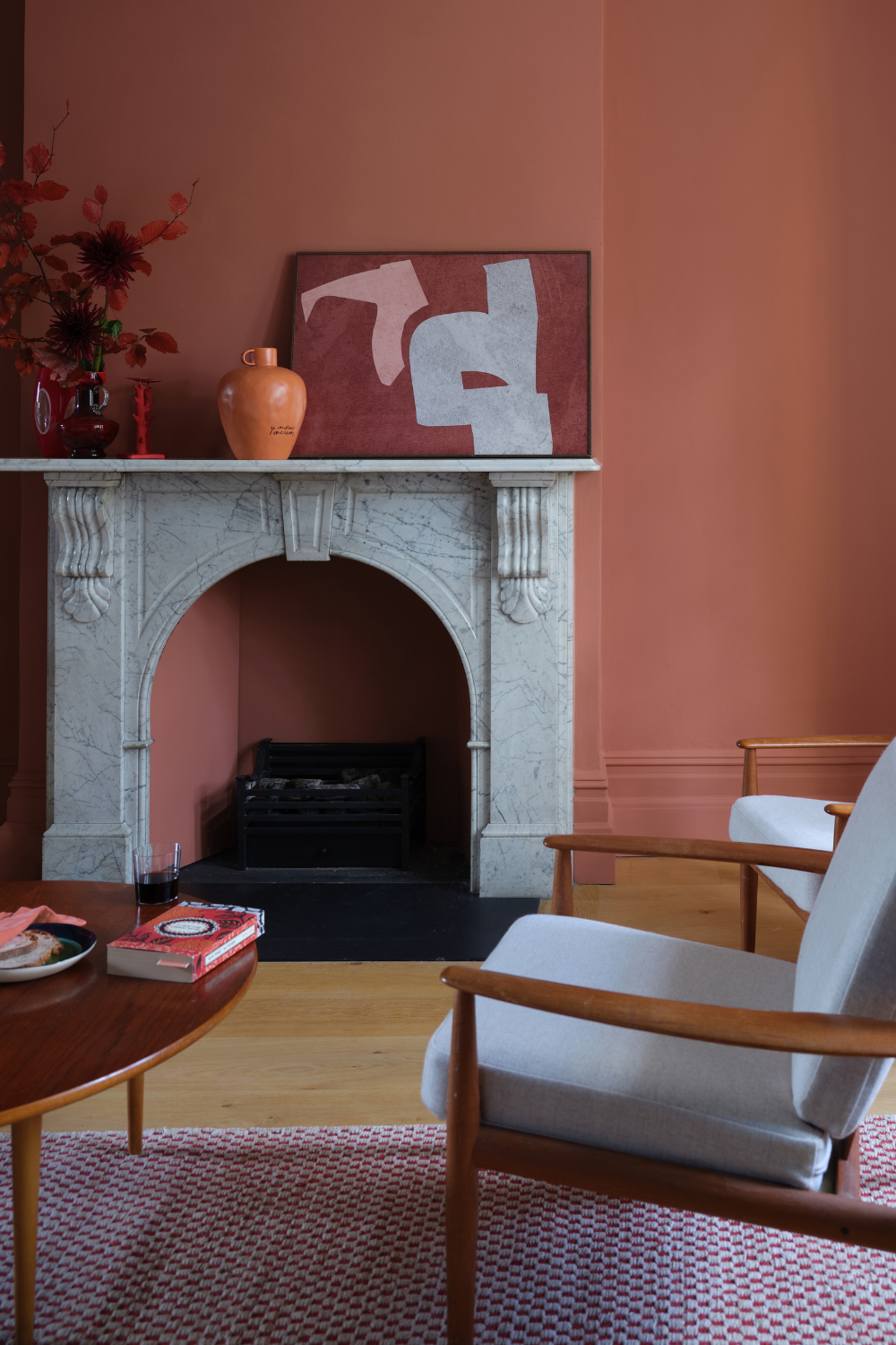 Terracotta living room featuring an ornate stone fireplace and mid-century-style furniture
