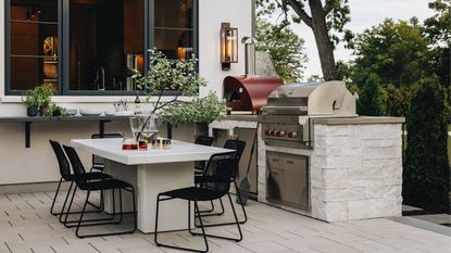 An outdoor space with a built in grill, and a pizza oven placed next to it