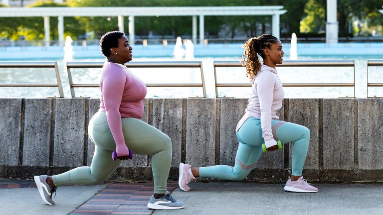 Two women perform lunges with some light dumbbells