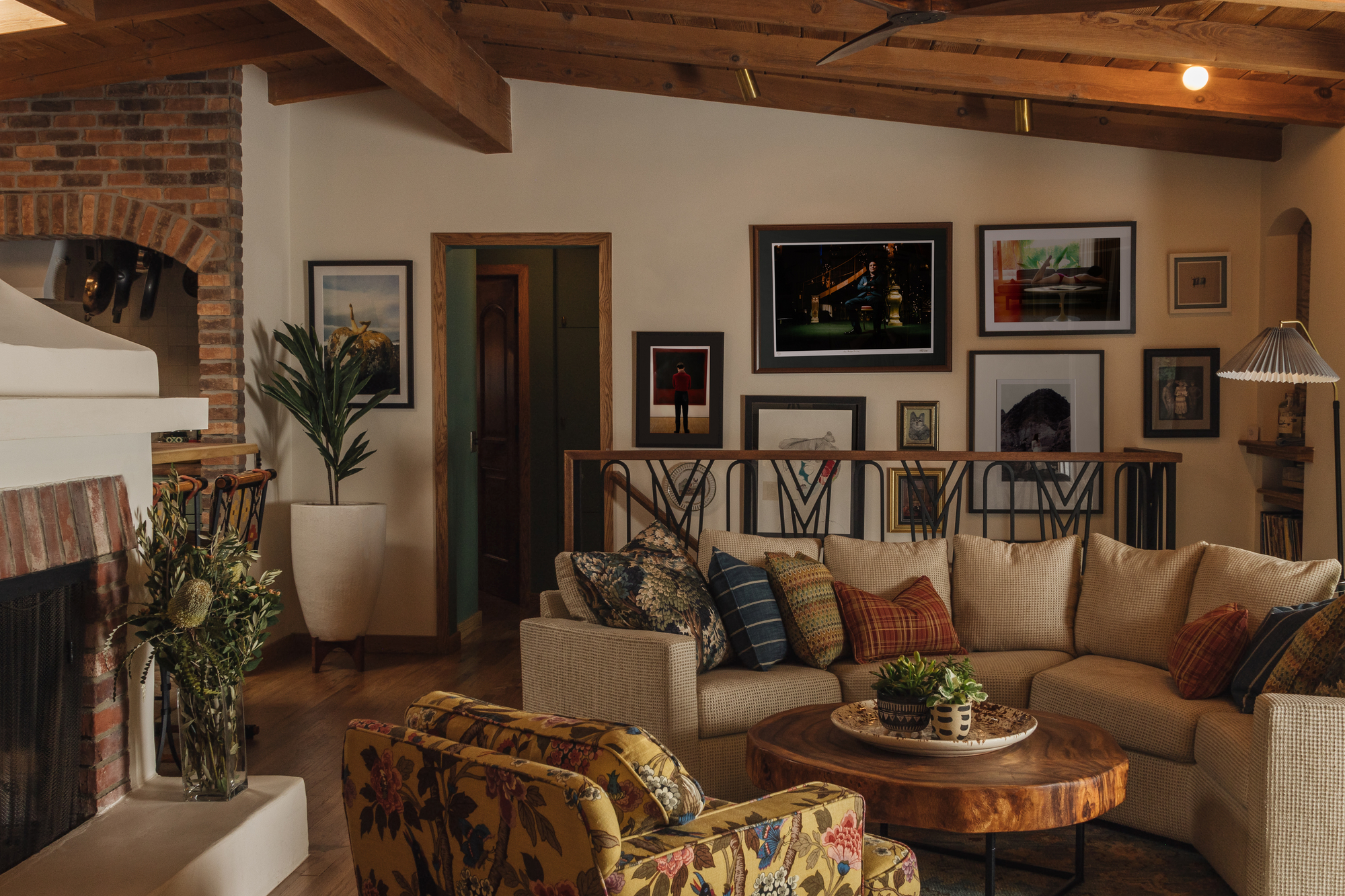 Wooden panelled and brick living room featuring a patterned chair, green plants and a beige sofa.