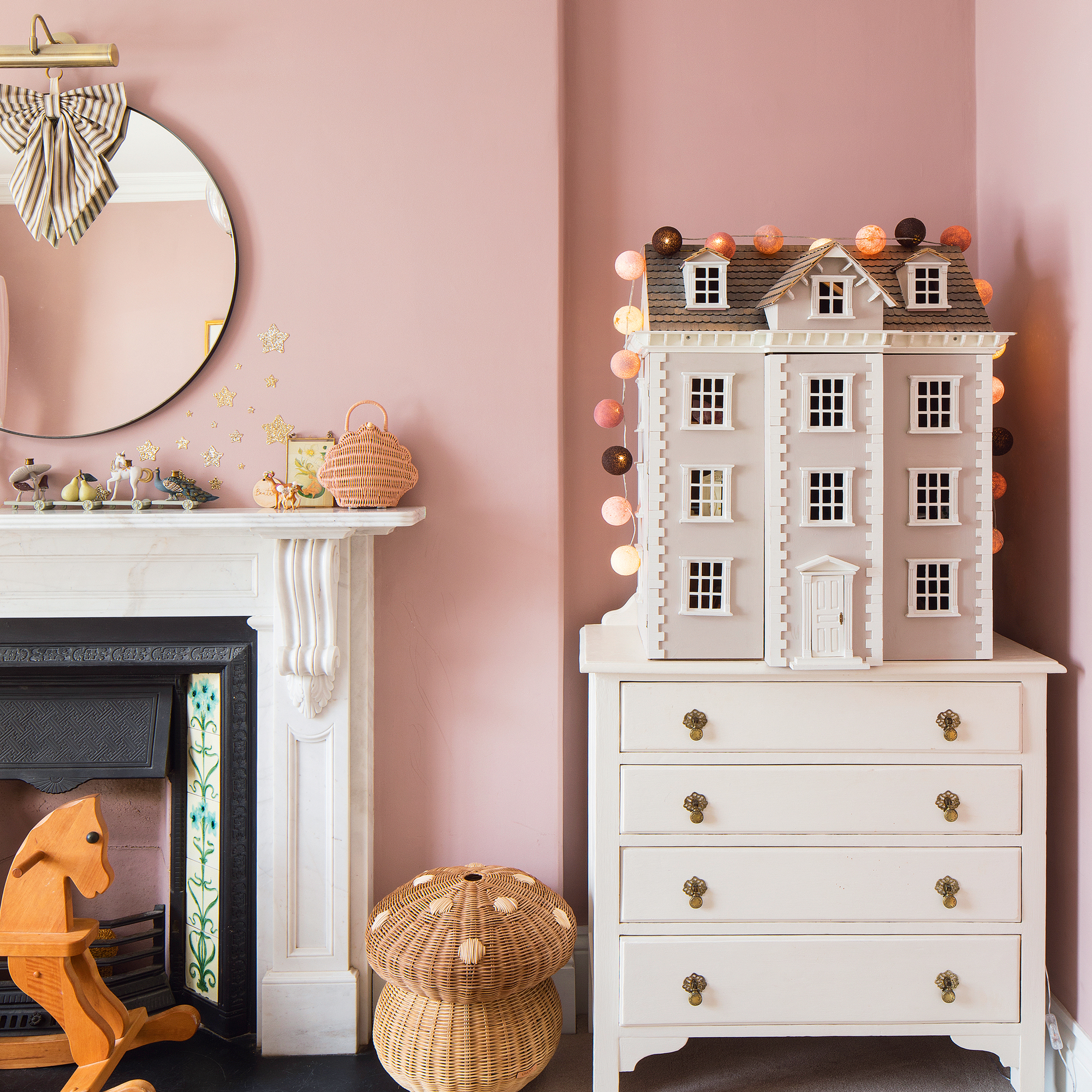 a child's bedroom with a doll's house on a chest of drawers beside a mantelpiece