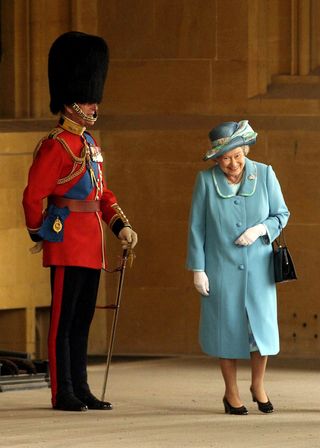 LONDON: Queen Elizabeth II gets a fit of the giggles as she walks past her husband Prince Philip, the Duke of Edinburgh who is standing to attention in his uniform and bearskin hat at Buckingham Palace in 2005. (Photo by Anwar Hussein/Getty Images)