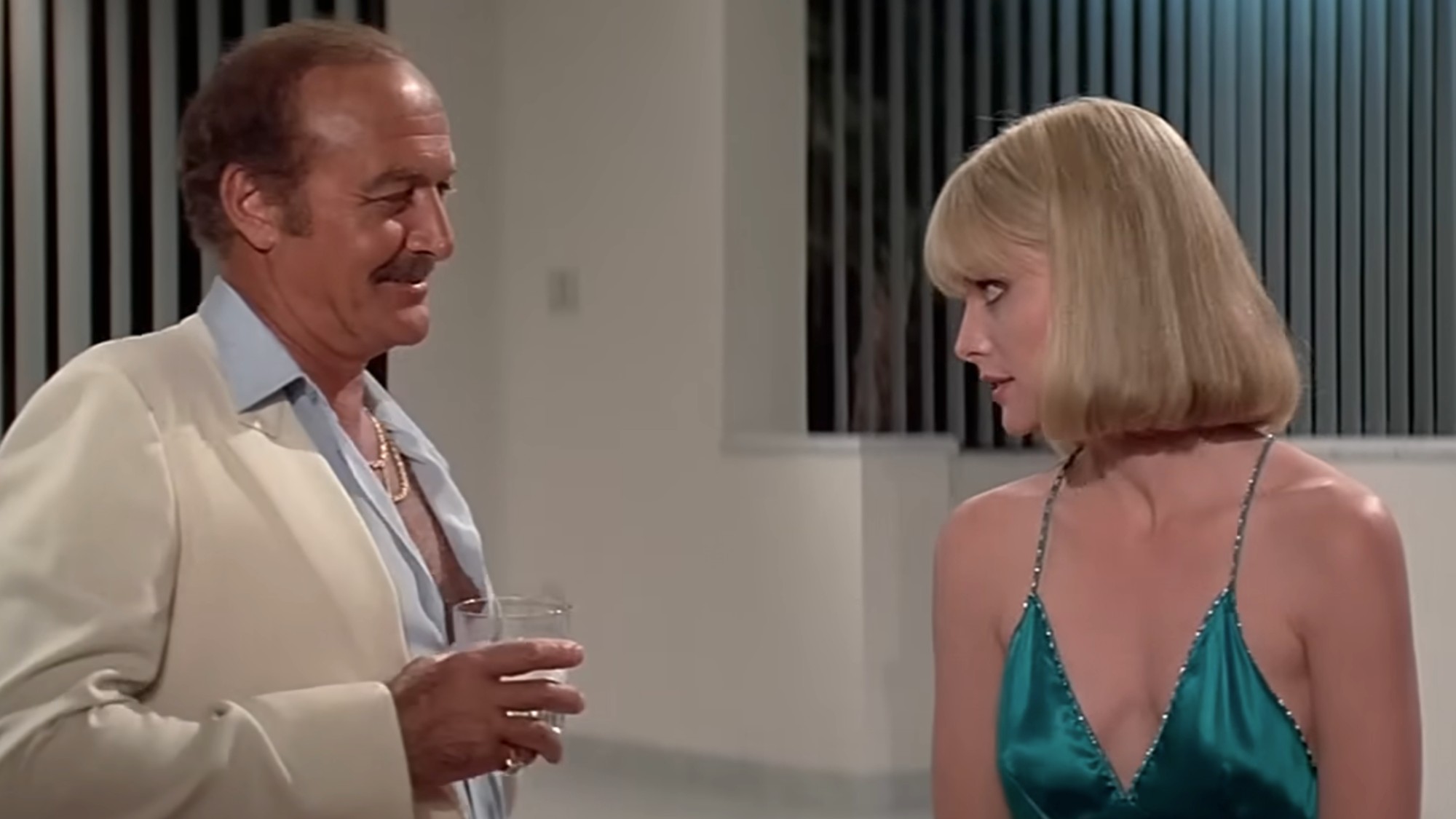 Robert Loggia in a white suit, talking to Michelle Pfeiffer in a green dress in Scarface
