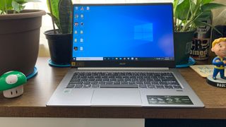 Laptopen Acer Swift 3 i et innemiljø med potteplanter og spilleffekter.