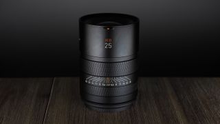 Hasselblad XCD 25V lens, on a wooden table, shot with dramatic light against a dark background