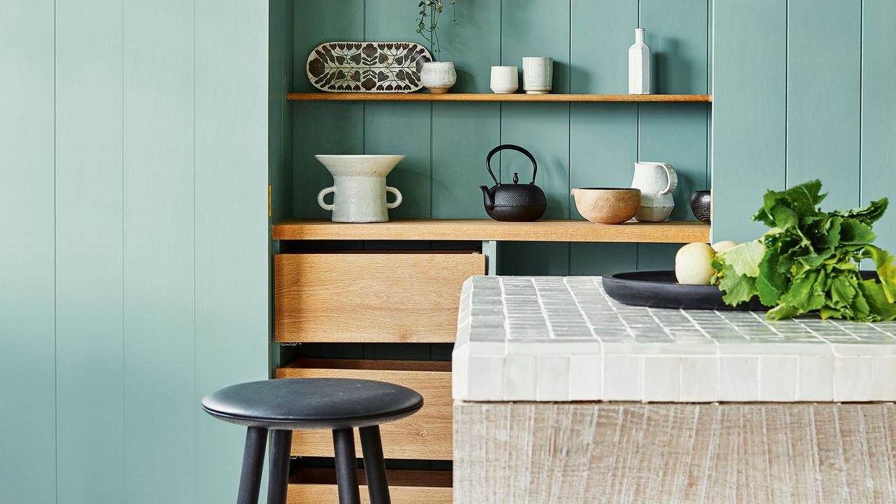 Light green wall panelled kitchen with wooden island topped with white tiles