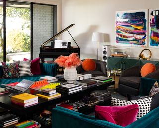 bold living room/music room with piano, record player, black and blue furniture, large coffee table with coffee table books, bright colours and pattern, painterly artwork