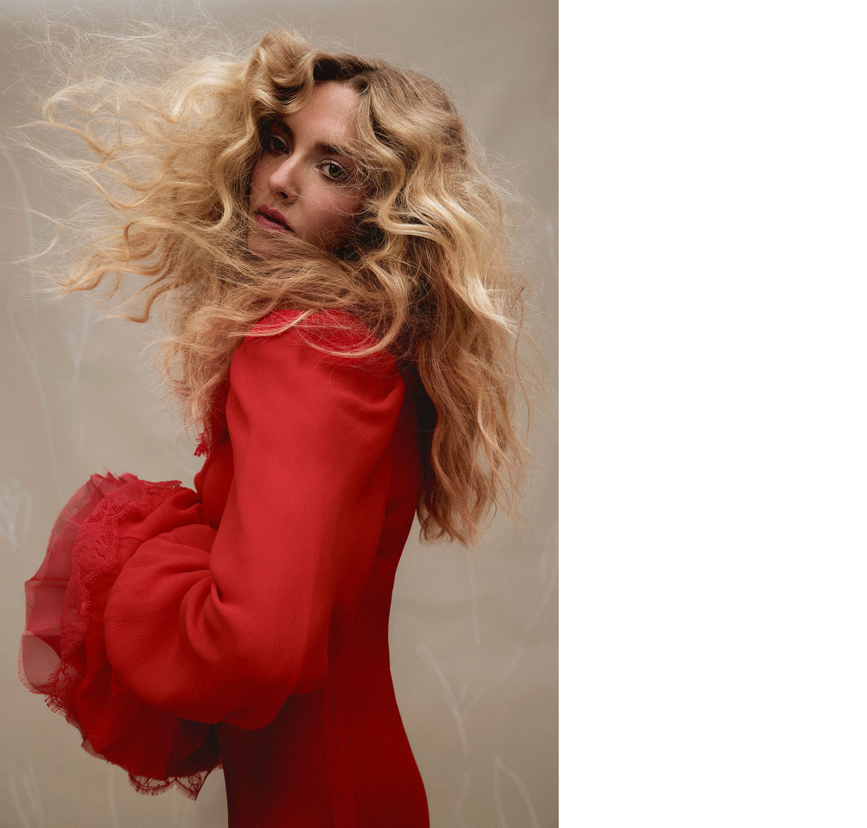 Amanda Seyfried for Who What Wear&#039;s December cover story. Looking off camera, Seyfried is seen wearing a red McQueen dress with her hands clasped showing off the long billowy sleeves.