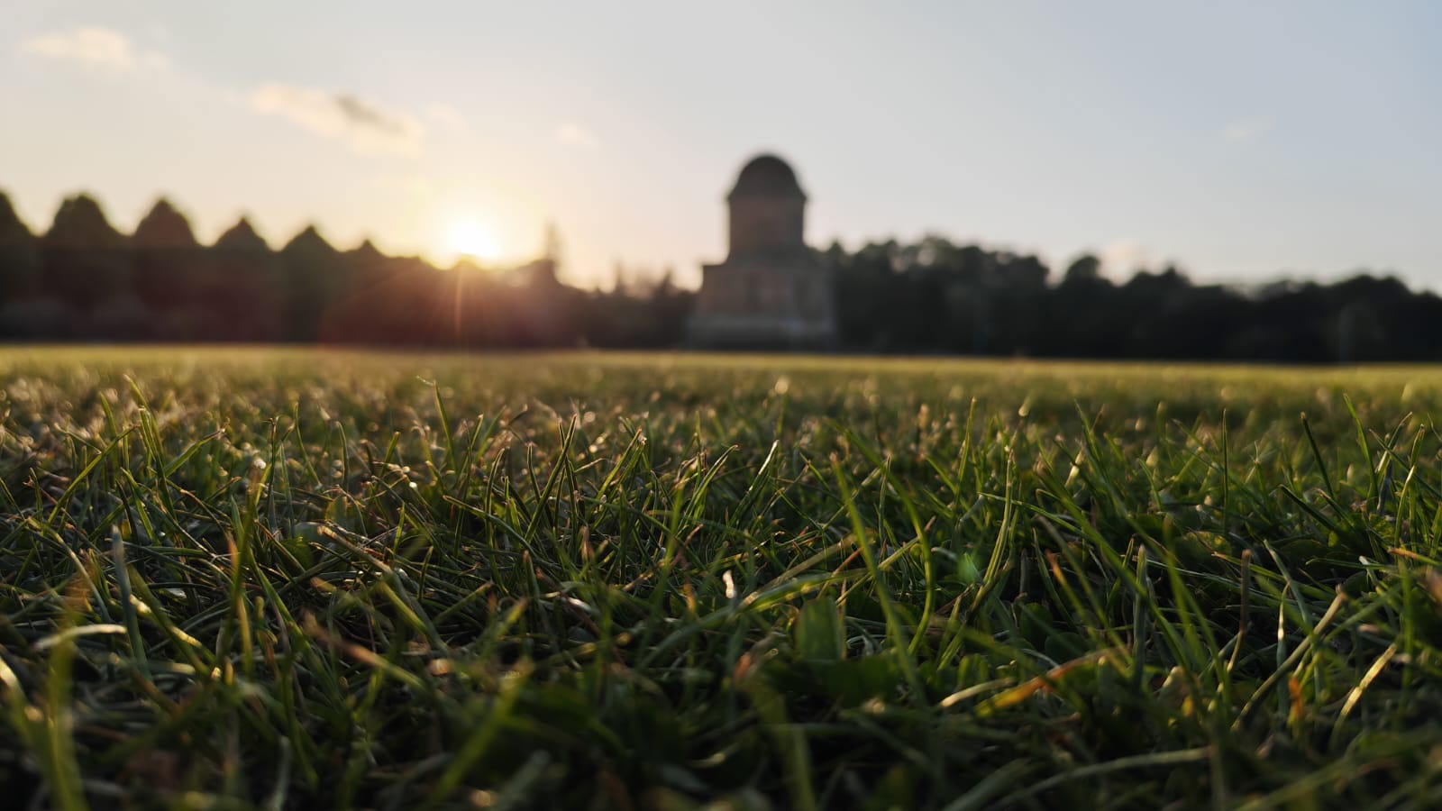 A sunset picture of a grass field with a monument in the background