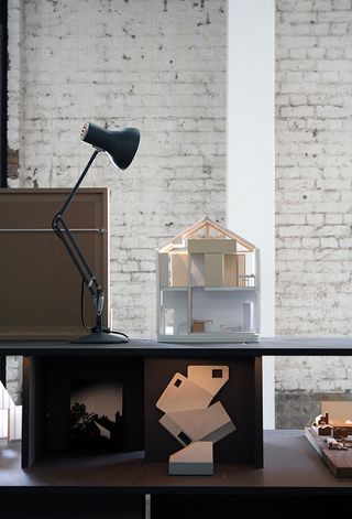 A selection of 3D models on black shelving and table lamp shining on them