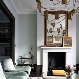Living room with vintage chandelier pendant reflected in mirror above fireplace