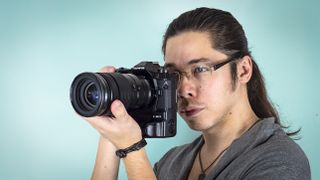 Reviewer James Artaius holding the Olympus M.Zuiko 40-150mm f/2.8 Pro lens, mounted to the Olympus OM-D E-M1X