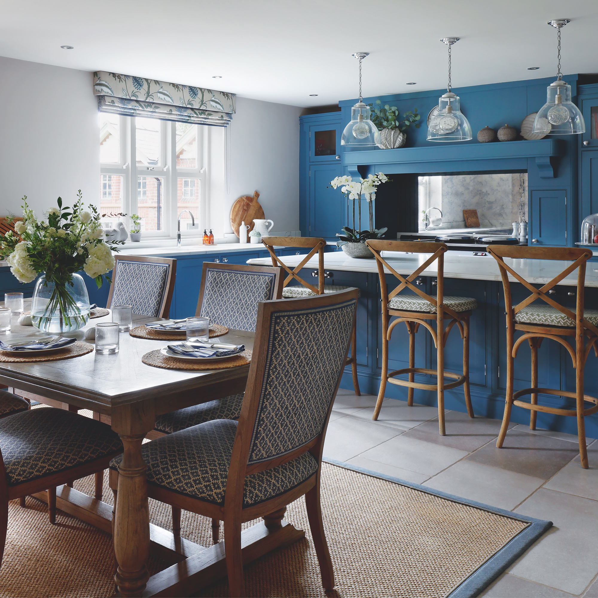 kitchen-diner with blue kitchen units and island, with dining table and upholstered dining chairs