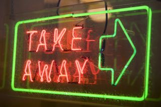 A green neon arrow sign with the word 'takeaway' in red neon next to it.
