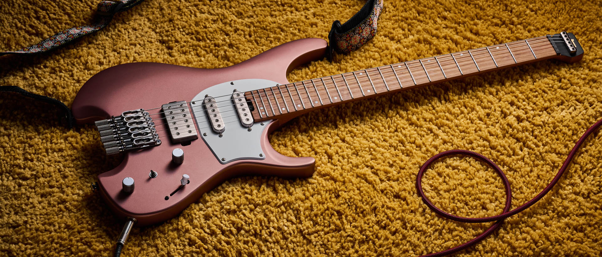 Ibanez Q54W: the headless electric guitar is finished in Copper Metallic Matte and photographed against a thick light-tan colored carpet.