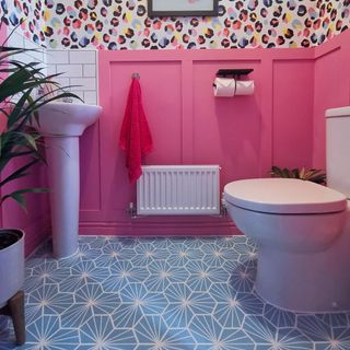 Colourful bathroom with pink and multi coloured patterned walls with sink and toilet