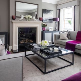 Grey living room with purple accents and a modern black framed coffee table