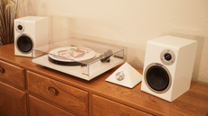 The Orange O Turntable on a wooden sideboard between two white speakers