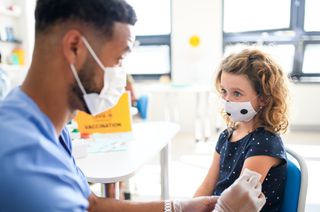 A healthcare worker vaccinates a young child.