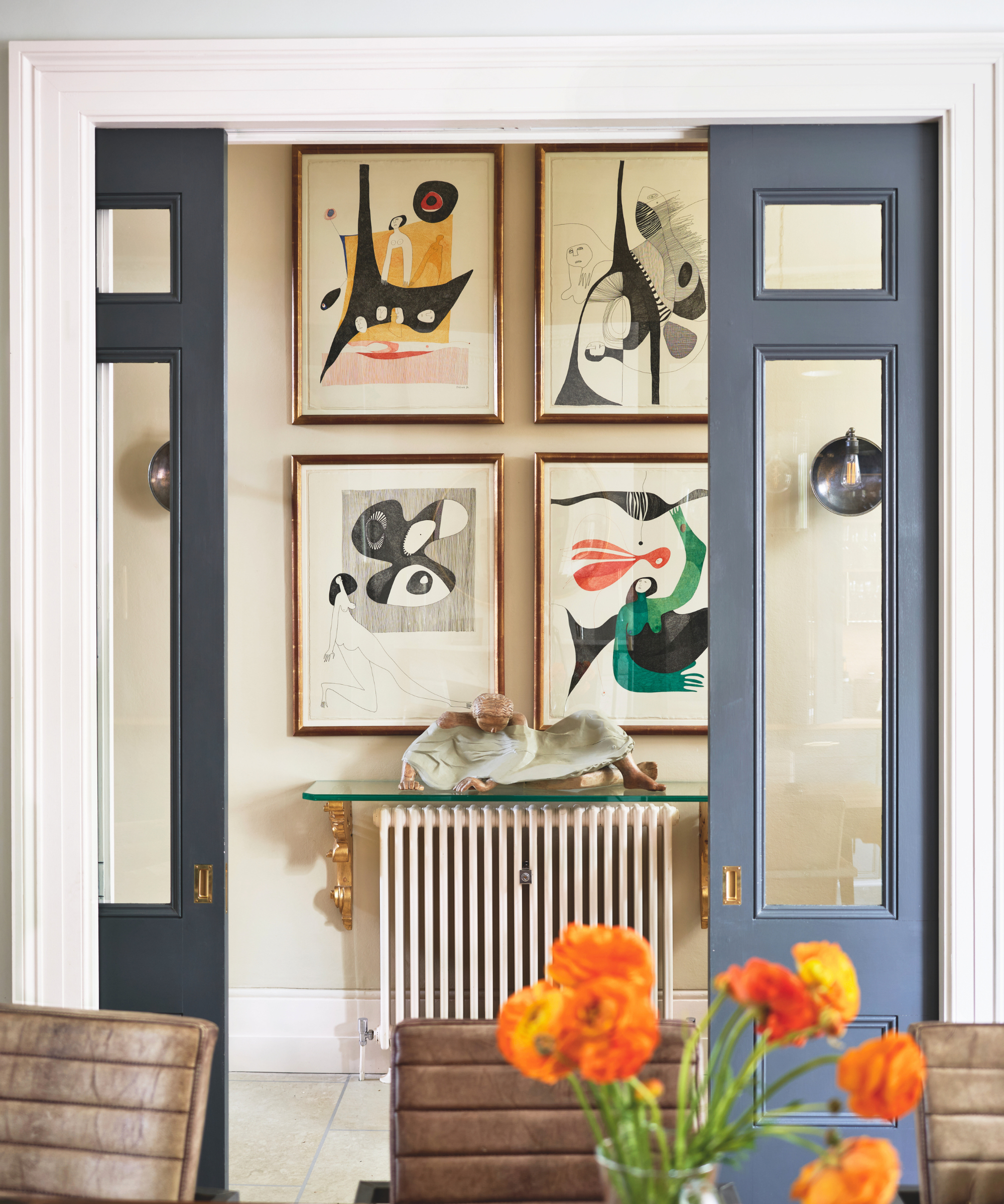 a room with pocket doors that are painted a slate blue color. In the hallway behind the doors is an arrangement of four pictures hanging from the wall
