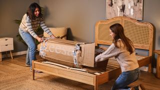 Two testers pull the compressed Leesa Legend Hybrid Mattress out of its box