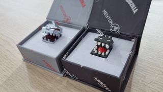 Custom keycaps from KeyTok in their respective cases, depicting the stylised heads of Godzilla, and Mechagodzilla