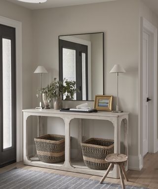 A neutral-toned foyer with a white side table and large wall mirror