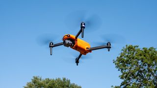 An orange drone in flight.