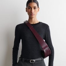Model wears grey merino top, burgundy crossbody bag