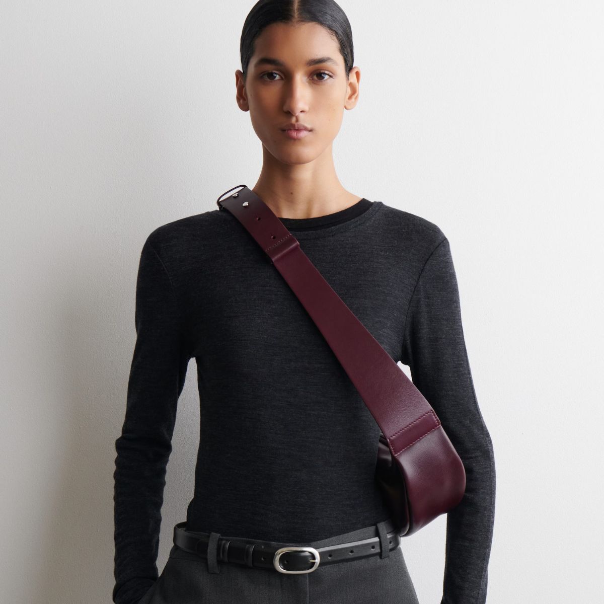 Model wears grey merino top, burgundy crossbody bag