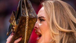 los angeles, ca october 19 singer adele uses her purse to hide from the tv camera while she sings along to her song being played to the audience while attending a game between the golden state warriors and the los angeles lakers on october 19, 2021 at staples center in los angeles allen j schaben los angeles times via getty images