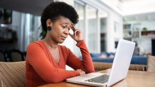 A frustrated-looking Black woman using a laptop