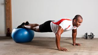 Man performs press-up with his feet resting on a gym ball