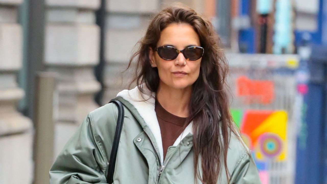 Katie Holmes wears an oversized bomber jacket, nylon pants, and Adidas shoes.