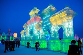 A structure made of ice is lit up in vibrant colours