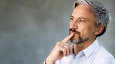 An older man looks thoughtful as he looks into the distance.