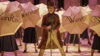 Timothée Chalamet stands in the middle of an umbrella filled musical number in Wonka.