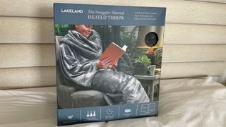 Lakeland The Snuggler Sleeved Heated Throw propped up, in its box, on the headboard of the bed