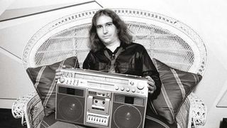 Portrait of American Rock composer, musician, and producer Jim Steinman (1947 - 2021), sitting in a large wicker chair, as he holds a boom box on his lap, New York, New York, April 30, 1981. 