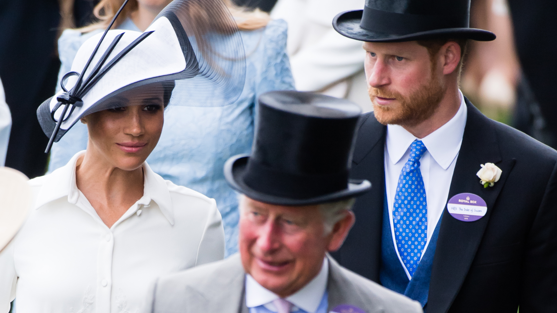 Meghan Markle wears a white dress with a matching hat, while Prince Harry and King Charles wears suits and top hats at Royal Ascot in 2018