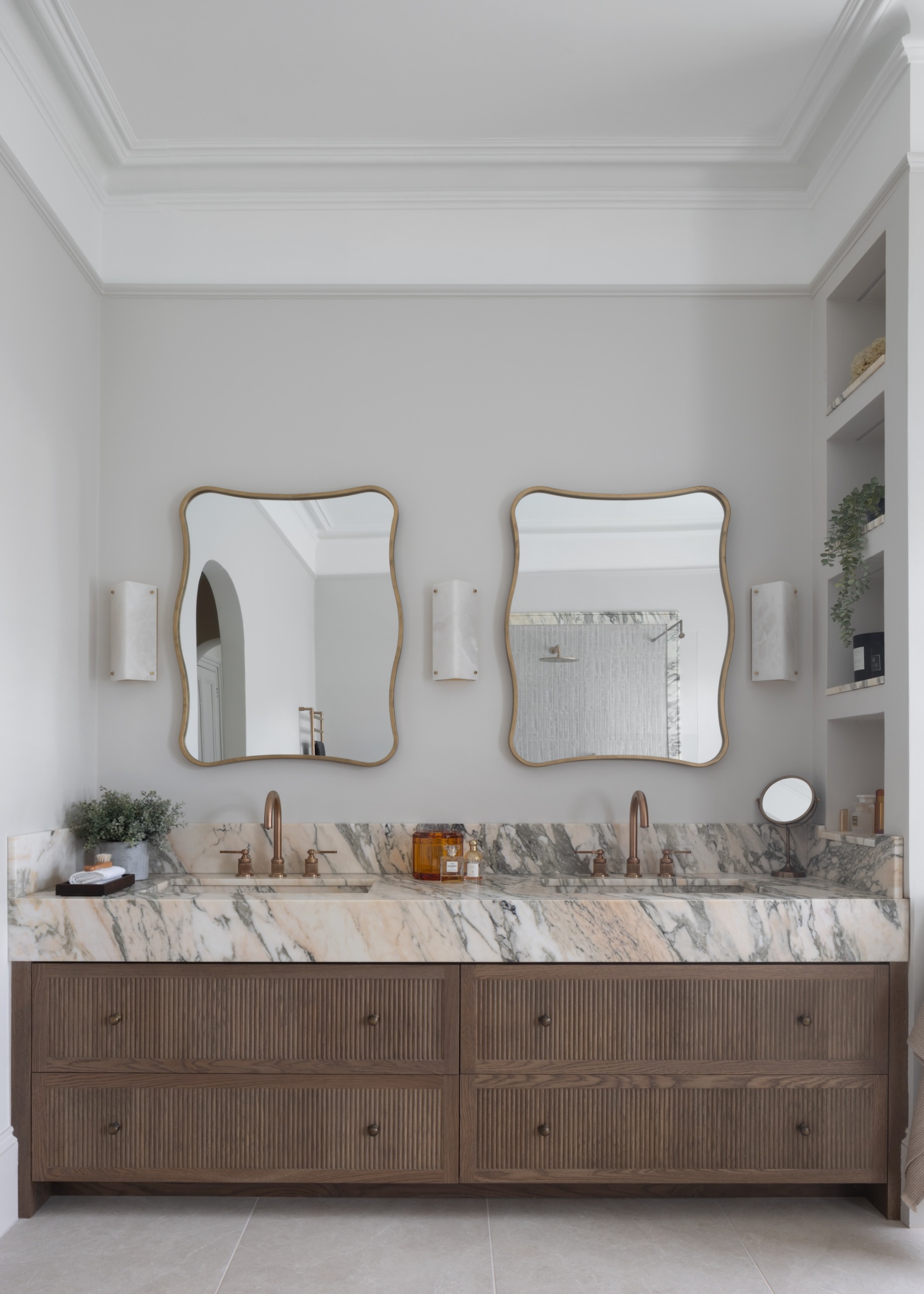 a double vanity basin with drawer storage, a chunky marble top and wall lights positioned either side of the mirrors