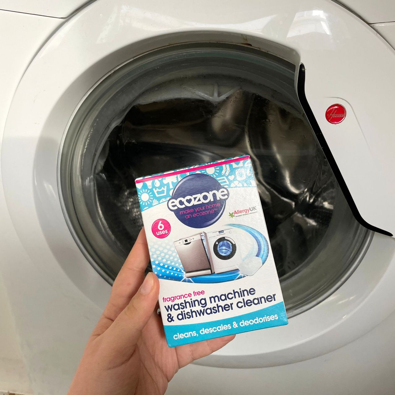 Holding a box of Ecozone washing machine cleaner in front of a washing machine