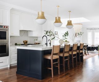 White kitchen with black island and wooden chairs